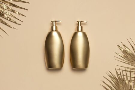Cosmetic mock up gold bottles. Cosmetics Branding Concept. Cosmetic containers, golden tropical palm leaves on beige background. Flat lay top view copy space. Cosmetic products, beauty background.の写真素材