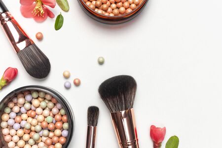 Professional makeup brushes powder blush balls with pink spring flowers on light background flat lay top view copy space. Beauty product, makeup, women's accessory, fashion. Cosmetic makeup Set.の写真素材