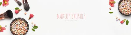 Professional makeup brushes powder blush balls with pink spring flowers on light background flat lay top view copy space. Beauty product, makeup, women's accessory, fashion. Cosmetic makeup Set.の写真素材