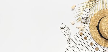 Summer women's white dress in black peas with natural wooden buttons straw hat golden palm leaf shells starfish on light background. Flat lay top view copy space. Women's beach fashion travel vacation.の写真素材