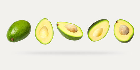Creative layout with ripe flying avocado halves on light background. Healthy food, diet, tropical...