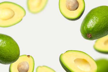 Creative layout with ripe flying avocado halves on light background. Healthy food, diet, tropical...