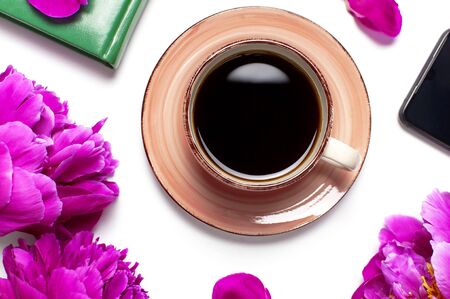 Beautiful flowers peonies, cup of coffee, green notebook, phone, pen on a white background top view with copy space. Female desktop, planning, morning coffee.の写真素材