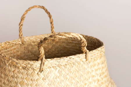 Empty straw wicker basket on a gray background. Fashionable bamboo basket, stylish interior item,...