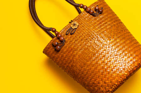 Beach wicker straw or rattan women's eco bag on yellow background. Flat lay top view copy space. Concept of travel. Summer bright background. Beach accessories, women s summer bag, hand bag, fashion.の写真素材