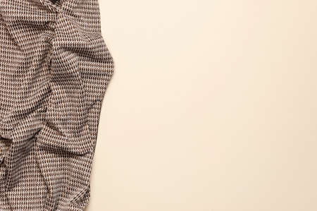 Natural brown cotton fabric with classic pattern foot on delicate beige background top view flat lay with copy space. Natural linen background. Eco textiles. Fabric texture. Fabric backdrop.の写真素材