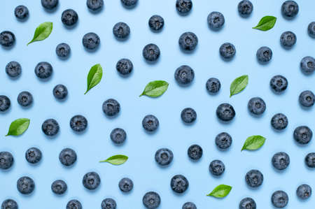 Fresh juicy blueberries with green leaves on blue background. Blueberries background. Flat lay top view copy space. Healthy berry, organic food, antioxidant, vitamin, blue food. Blueberry frameの写真素材