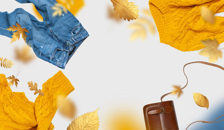 Yellow flying womens knitted sweater blue jeans brown leather bag golden autumn leaves on gray...