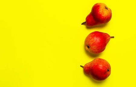 Juicy ripe fresh red pears on yellow background flat lay top view copy space. Creative background...