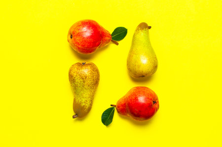 Juicy ripe fresh green and red pears on yellow background flat lay top view copy space. Creative background with pears and green leaves. Fruit background, organic healthy food. Harvest conceptの写真素材