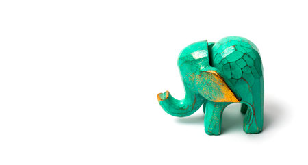 Figurine of a green wooden elephant with gilding isolated on white background. Decorative figurine of an elephant, hand carved wooden model of an elephant. Statuette, toy, souvenir from Asia.の写真素材