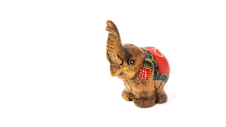 Figurine of a wooden elephant with pattern on the back isolated on white background. Decorative figurine of an elephant, hand carved wooden model of an elephant. Statuette, toy, souvenir from Asia.の写真素材
