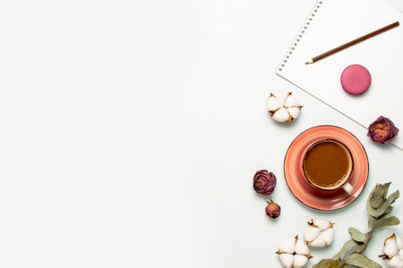 Flat lay autumn composition. Cup of coffee pink knitted women's sweater or warm plaid cotton flowers dry rose eucalyptus macaroon cake blank notebook pencil on white background top view. fall concept.の写真素材