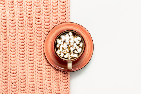 Flat lay autumn composition. Cup of coffee with marshmallows, pink knitted women's sweater or warm plaid on light gray white background top view copy space. Autumn, fall concept. Cozy lifestyle details.の写真素材