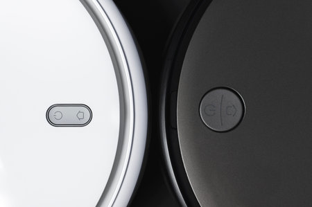 White and black modern robot vacuum cleaner on black background flat lay. New technologies, quick...