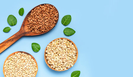 Green buckwheat, sprouted buckwheat in wooden bowls brown buckwheat grains in wooden spoon with green leaves on blue background. Flat lay top view. Healthy vegan food eco products diet organic harvest.の写真素材