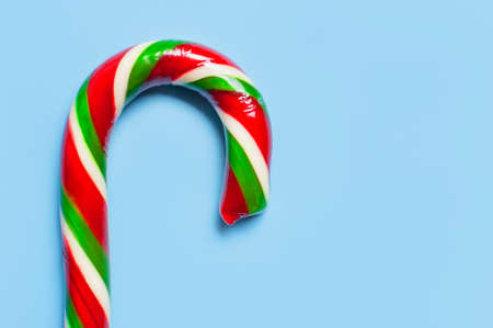 Traditional Christmas candy cane, lollipop on blue background flat lay top view macro photo. New year food concept. Festive decor, sweetness, caramel candy. Christmas holiday symbol, decoration.の写真素材
