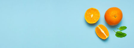 Fresh juicy whole and sliced orange, green leaves of mint on blue background. Flat lay top view....