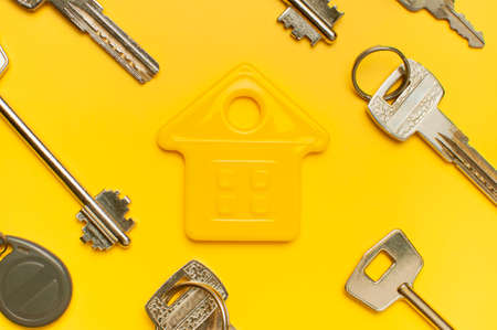 House symbol and metal keys on yellow background flat lay top view copy space. house door keys. Concept of buying home, apartment. Renting a house, real estate. Mortgage, credit, real estate insurance.の写真素材