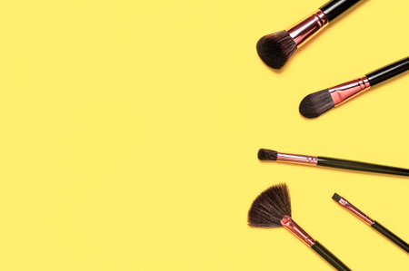 Professional makeup brushes on Illuminating yellow background flat lay top view.