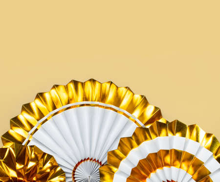 Festive white and gold paper fans for party, birthday, holiday, wedding on beige background top view copy space. origami. decorative objects. Colorful abstract background. Festive trendy backdrop.の写真素材