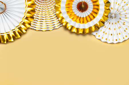 Festive white and gold paper fans for party, birthday, holiday, wedding on beige background top view...