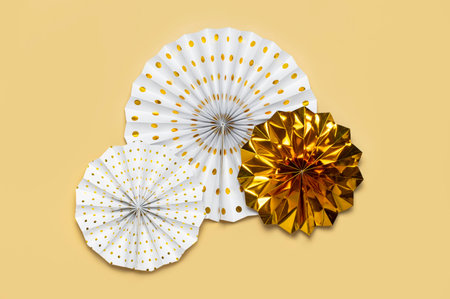 Festive white and gold paper fans for party, birthday, holiday, wedding on beige background top view...