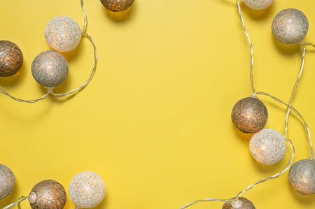 Gray white festive garland on yellow background flat lay top view. Cotton Balls Garland. Round bulbs...