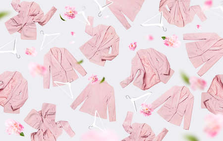 Creative spring clothing concept. Womens fashionable flying pink blazer flowers peonies white wooden hanger on gray background. Female fashion, stylish fabric cotton jacket. Sale, springtime discounts.の写真素材