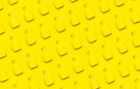 Yellow plastic cosmetic bottle container with dispenser on yellow background flat lay pattern Clean container without label for soap gel cream lotion shampoo bath foam. Beauty spa branding mockups.の写真素材