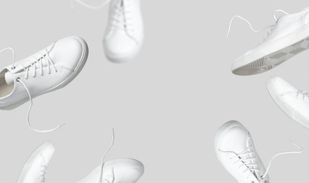 Flying white leather womens sneakers isolated on gray background, different kind. Fashionable stylish sports casual shoes. Creative minimalistic layout with footwear. Advertising for shoe store, blog.の写真素材