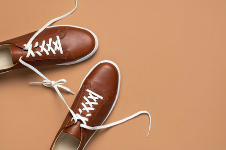 Leather brown men's sneakers with white laces and rubber soles on beige background. Flat lay top view. Men's sports casual shoes. fashionable sneakers. Male fashion hipster footwear Minimal background.の写真素材