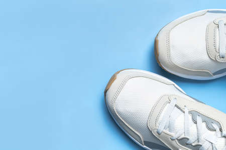 Pair of light men's sneakers on blue background. Sports shoes, footwear for fitness, running, training. Minimalistic background with sneakers. Healthy lifestyle concept. Flat lay top view copy space.の写真素材