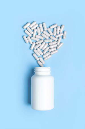 Pills, tablets, vitamins, food supplement in capsules in shape of heart, white plastic bottle on...