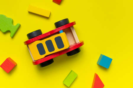 Wooden children's toy red fire truck, Multi-colored children's constructor made of natural wood on yellow background flat lay top view. Kids natural eco toys. Developing toys, game. special equipment.の写真素材