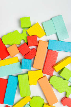 Multi-colored children's constructor made of natural wood on light gray background flat lay top view. Colored children's bricks for construction. building blocks background. Developing toys, game.の写真素材