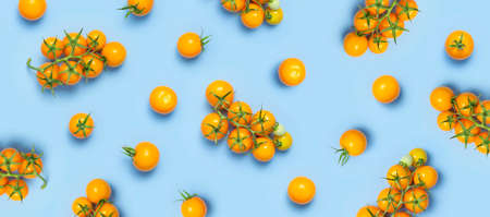 Ripe fresh yellow orange tomatoes with green tails on blue background flat lay top view. cherry tomatoes. Vegetables, healthy vegan organic food, harvest concept, tomatoes pattern layout, cooking.の写真素材