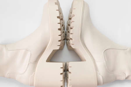Fashionable beige leather women's boots with rough sole on light gray background top view. Trendy spring autumn shoes. Creative minimalist shoes background. Layout with footwear Mock up.の写真素材