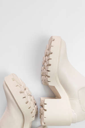 Fashionable beige leather women's boots with rough sole on light gray background top view. Trendy spring autumn shoes. Creative minimalist shoes background. Layout with footwear Mock up.の写真素材