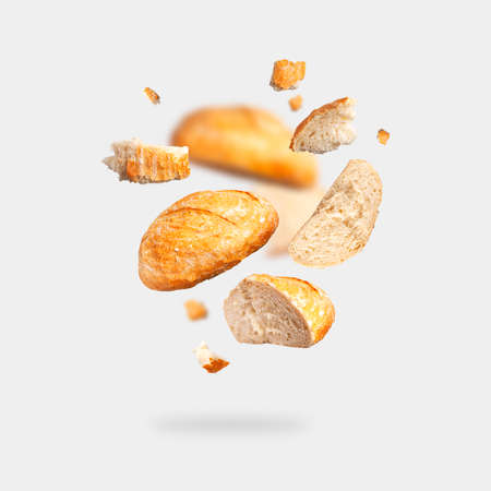Classic white wheat bread flying on gray background. Round whole and pieces crispy fresh bread, healthy organic food, traditional pastries, bakery. Creative food concept for advertising, design.の写真素材