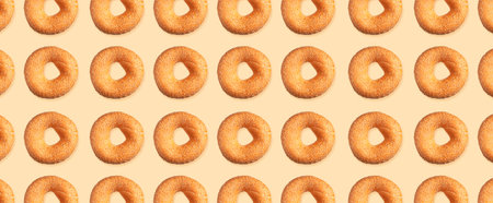 Creative food, baking pattern. Fresh round wheat bagel with sesame seeds on beige background. Crispy...
