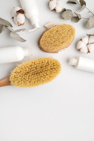 Wooden body massage brushes with natural bristles, white clean cosmetic bottles, eucalyptus branch,...