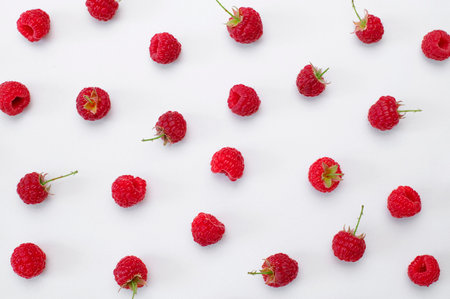 Ripe juicy fresh raspberries on white background flat lay top view. Raspberry pattern. Organic raspberries, healthy food, vitamins, summer berry fruit background. Raspberry harvest.の写真素材