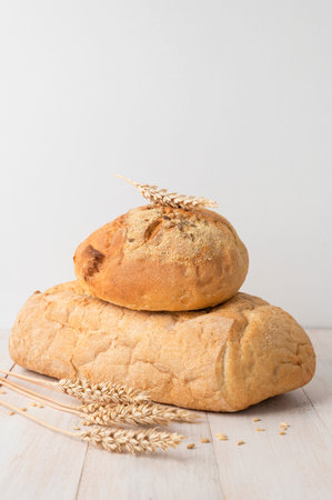 Fresh white wheat bread, round classic, ciabatta, french baguette, wheat ears and grains on white...