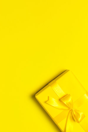 holiday concept. Yellow gift box with ribbon and bow on bright yellow background flat lay top view copy space. Surprise, gift for birthday, mother's day, March 8, Christmas. Congratulations.の写真素材