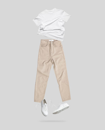 Clean white Unisex T-shirt. White flying cotton T-shirt, beige jeans, white leather sneakers isolated on gray background. branding clothes. Mock up for your design. Spring Summer Women's Clothing.の写真素材