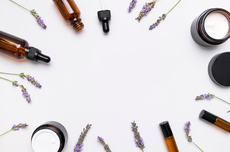 Natural organic cosmetics with lavender extract on white background flat lay top view. Glass bottles with pipette, jars of face cream and lavender flowers. Aromatherapy, spa, body care mock up.の写真素材