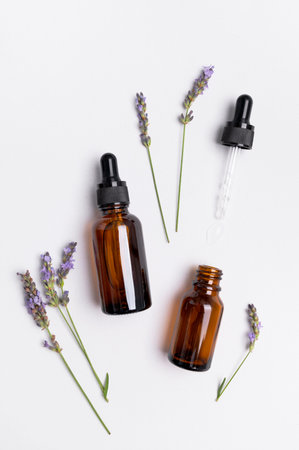 Brown glass bottles with pipette with lavender essence oil, lavender flowers on white background top view. Natural cosmetics with lavender extract, aromatherapy, spa, body care, mock up.の写真素材