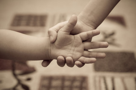 Two children of 2 and 6 years hold hands