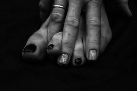 Female legs, hands. beautiful feet and palms on a black background, close-up. Black and white photography, natural light.の写真素材